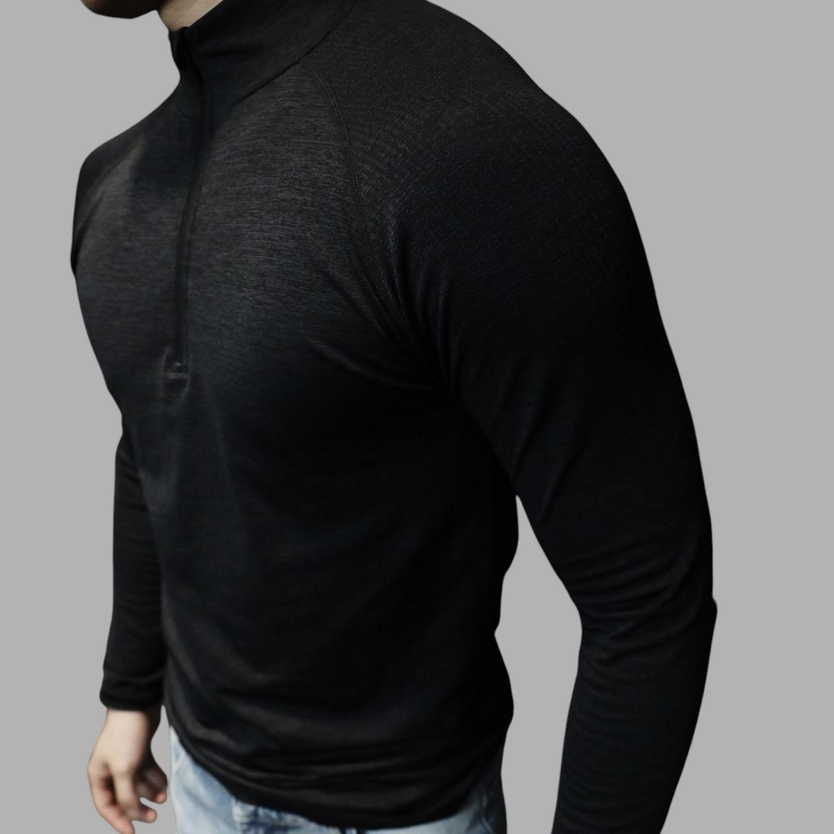 ASCEND black long sleeve zip-up tee with shoulder detailing worn by a man in a gym setting
