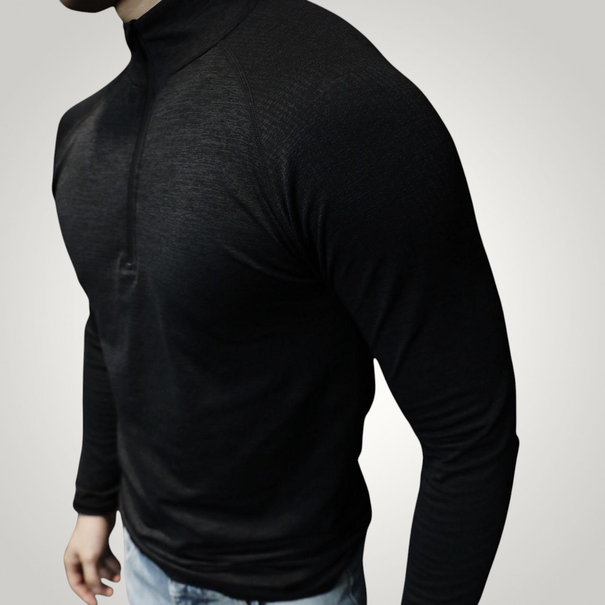 ASCEND black long sleeve zip-up tee with shoulder detailing worn by a man in a gym setting