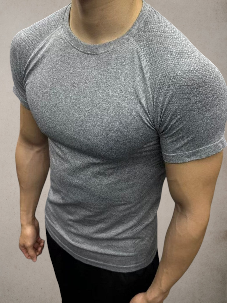ASCEND gray seamless compression short sleeve tee with textured shoulder detailing on a muscular model in a gym
