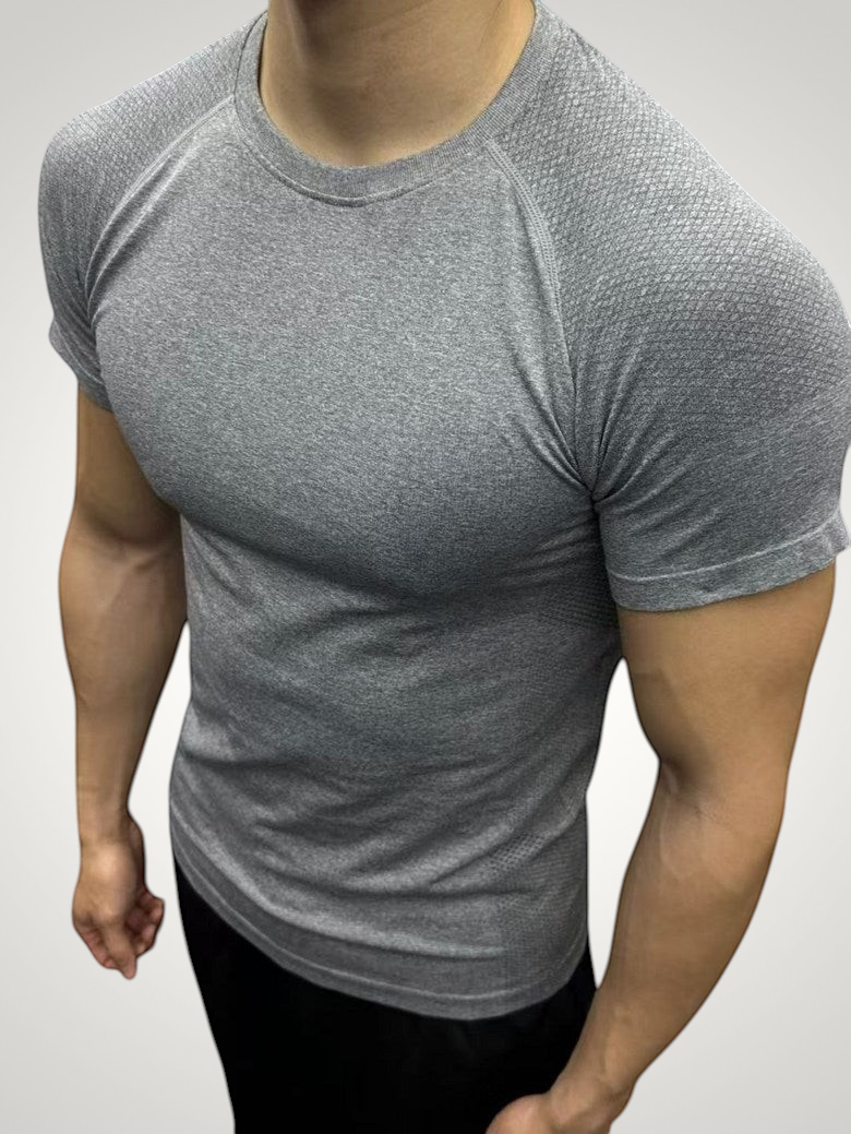ASCEND gray seamless compression short sleeve tee with textured shoulder detailing on a muscular model in a gym